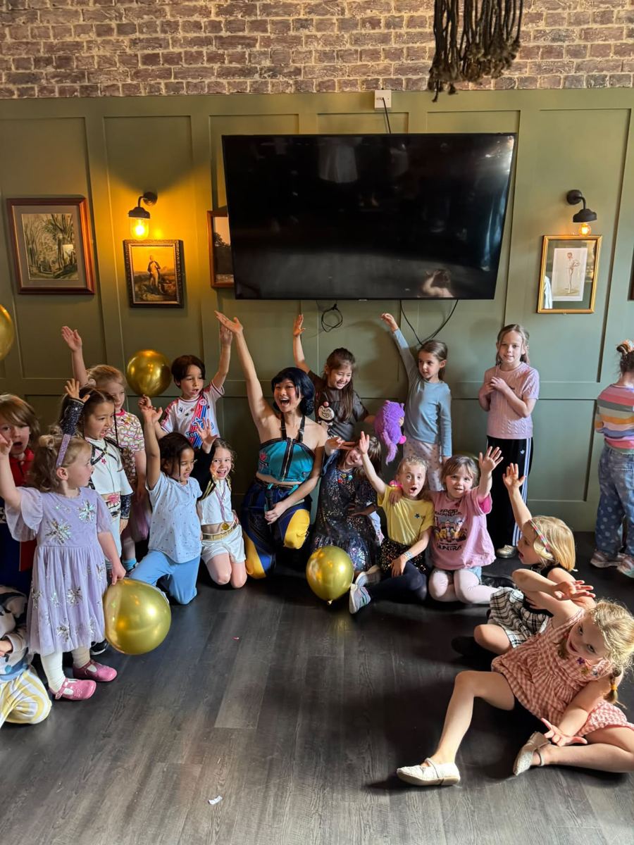 Performer kneeling with a large group of excited children